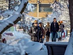 学生们裹得严严实实，走在被雪覆盖的校园小路上.